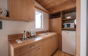 Area cucina della Mobile Home Basic Family al Wecamp Pedraforca in Spagna, con mobili in legno e elettrodomestici.