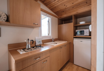 Zona de cocina del Mobile Home Basic Family en Wecamp Pedraforca, España, con muebles y electrodomésticos de madera.