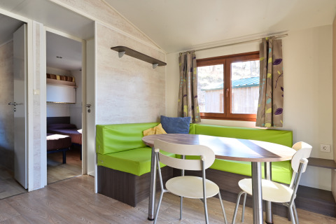 Eethoek met groene zitbank en ronde tafel in Mobile Home Basic Family+ Panoramic van Wecamp Pedraforca.