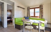 Eethoek met groene bank en ronde tafel in Mobile Home Basic Family+ Panoramic bij Wecamp Pedraforca.