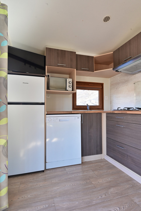 Moderne kitchenette met vaatwasser, koelkast, microgolfoven en houten kasten in een gezinslodge.