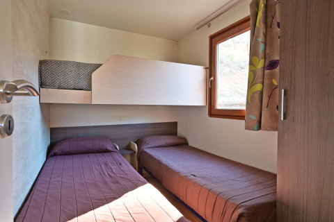 Kamer in Mobile Home Basic Family+ Panoramic bij Wecamp Pedraforca, Spanje, met drie eenpersoonsbedden.