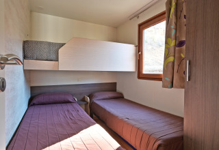 Kamer in Mobile Home Basic Family+ Panoramic bij Wecamp Pedraforca, Spanje, met drie eenpersoonsbedden.