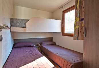 Et værelse på Mobile Home Basic Family+ Panoramic på Wecamp Pedraforca i Spanien med tre enkeltsenge.