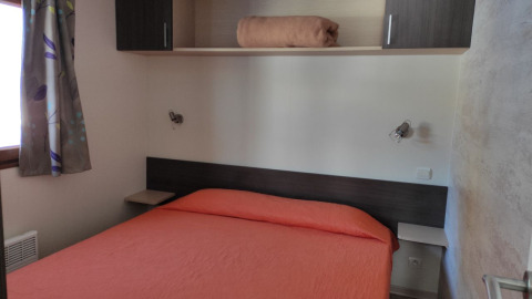 Slaapkamer in Mobile Home Basic Family+ Panoramic met oranje beddengoed bij Wecamp Pedraforca, Spanje.