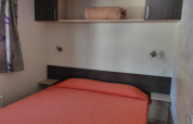 Slaapkamer in Mobile Home Basic Family+ Panoramic met oranje beddengoed bij Wecamp Pedraforca, Spanje.