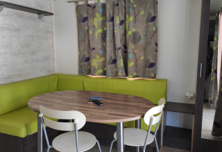 Eethoek van de Mobile Home Basic Family+ Panoramic met groene zitbanken en tafel bij Wecamp Pedraforca.
