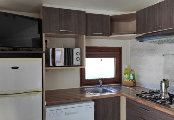 Moderne tekøkken i Mobile Home Basic Family+ Panoramic med hvidevarer og træskabe på Wecamp Pedraforca.