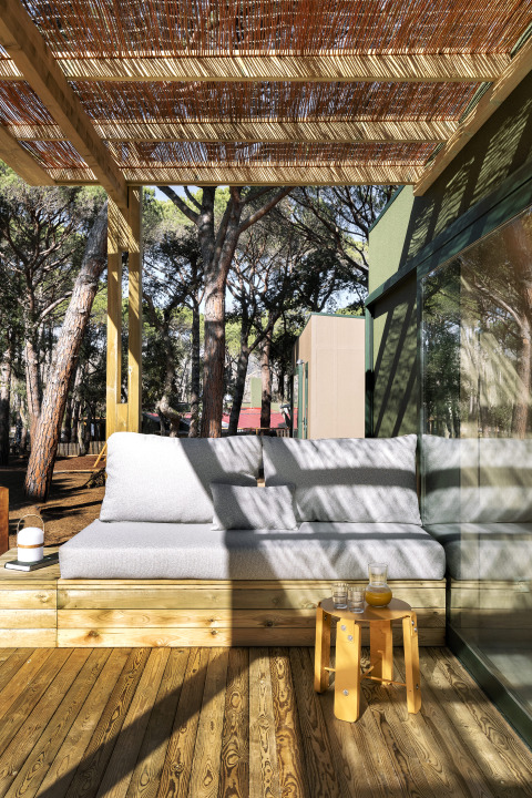 Buitenlounge met sofa en houten terras onder pergola bij Mobil Home Couple, Wecamp Pedraforca, Spanje.