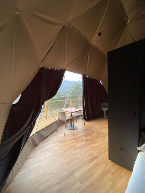 Binnenaanzicht van de Domo Family-koepel bij Wecamp Pedraforca in Spanje met houten vloer en balkon.