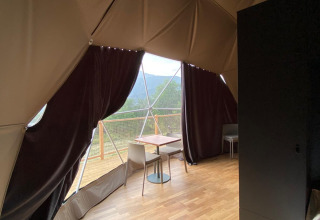 Binnenaanzicht van de Domo Family-koepel bij Wecamp Pedraforca in Spanje met houten vloer en balkon.