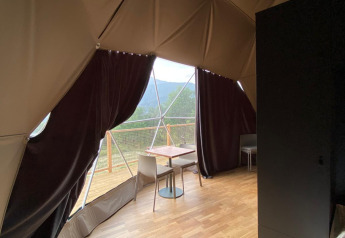 Indvendig udsigt fra Domo Family-kuppelen på Wecamp Pedraforca i Spanien med trægulv og balkon.