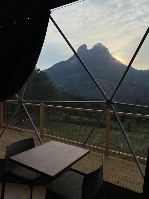 Uitzicht vanuit Domo Family koepel bij Wecamp Pedraforca in Spanje, met tafel, stoelen en berglandschap.