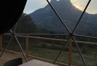 Uitzicht vanuit Domo Family koepel bij Wecamp Pedraforca in Spanje, met tafel, stoelen en berglandschap.