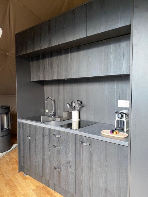 Moderne zwarte kitchenette in de Domo Family-koepel bij Wecamp Pedraforca, Spanje, met koffiemachine en wasbak.