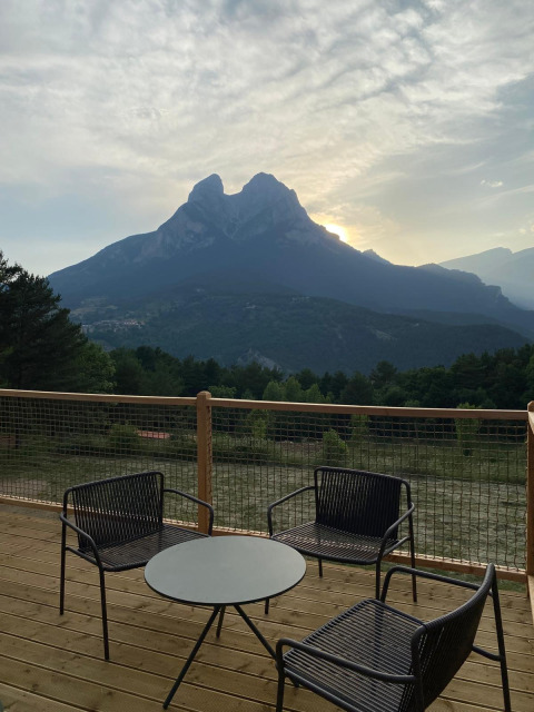 Terras met stoelen en tafel bij 'Domo' Family, Wecamp Pedraforca in Spanje, uitzicht op de berg bij zonsopgang.
