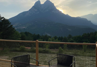 Terras met stoelen en tafel bij 'Domo' Family, Wecamp Pedraforca in Spanje, uitzicht op de berg bij zonsopgang.