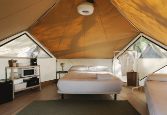 Interior of Bell Tent safari tent at Wecamp Jávea, Spain, with double bed, shelves, and lighting.