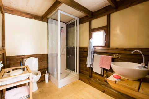 Badezimmer im Air Dreamer 3 Safarizelt mit Holzwänden, Dusche, Waschbecken und Toilette.