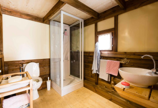 Badkamer in de Air Dreamer 3 safaritent met houten panelen, douche, wastafel en toilet.