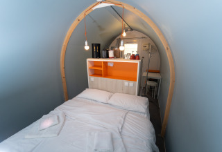 Interior de una tienda safari acogedora con cama doble, techo arqueado y comodidades modernas en Italia.