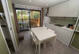 Cocina de lodge moderna con mesa blanca, cuatro sillas y acceso a terraza exterior con árboles.