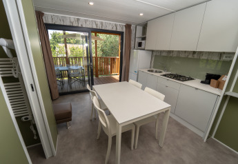 Cocina de lodge moderna con mesa blanca, cuatro sillas y acceso a terraza exterior con árboles.