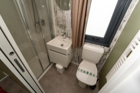 Foto de un baño pequeño en una cabaña, con ducha, lavabo cuadrado y WC junto a una ventana con cortina.