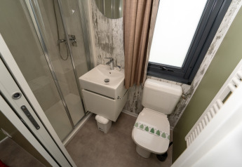 Foto de un baño pequeño en una cabaña, con ducha, lavabo cuadrado y WC junto a una ventana con cortina.