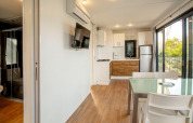 Interior moderno de la cabaña Cottage Next XL Panorama con cocina, comedor y vista, en Weekend Glamping Resort, Italia.