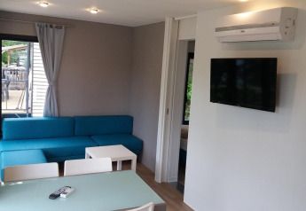 Stue i Cottage Next XL Panorama på Weekend Glamping Resort i Italien, med moderne sofa, spisebord og tv.