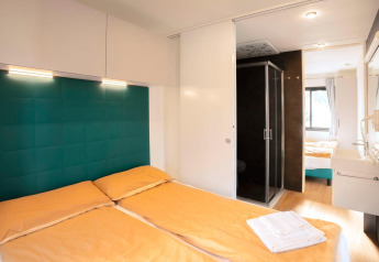 Værelse i Cottage Next XL Panorama med dobbeltseng, moderne indretning, badeværelse og stort vindue.