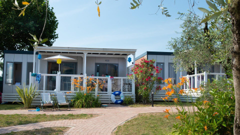 Cottage Next XL superior lodge with terrace, lounge chairs, and vibrant garden at Weekend Glamping Resort, Italy.