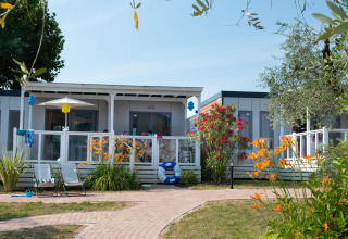 Cottage Next XL superior lodge with terrace, lounge chairs, and vibrant garden at Weekend Glamping Resort, Italy.