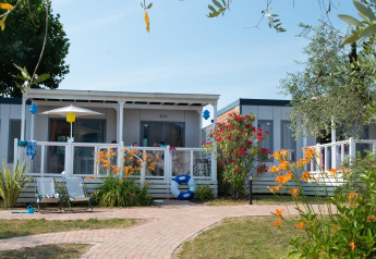 Lodge Cottage Next XL supérieur avec terrasse, transats et jardin fleuri au Weekend Glamping Resort, Italie.