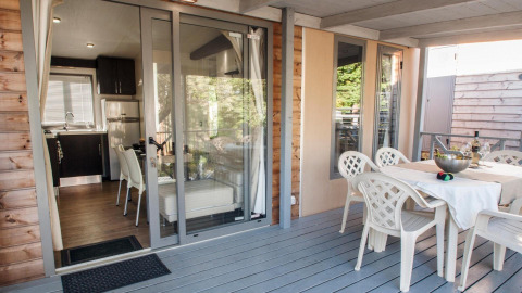 Outdoor terrace and indoor kitchen area of Cottage Next XL superior at Weekend Glamping Resort, Italy.