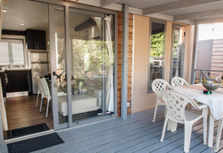 Outdoor terrace and indoor kitchen area of Cottage Next XL superior at Weekend Glamping Resort, Italy.