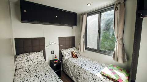 Room with two single beds, large windows, and letter-pattern bedding at Cottage Next XL superior, Weekend Glamping Resort, Italy.