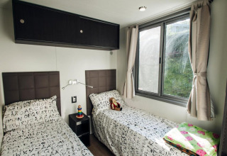 Room with two single beds, large windows, and letter-pattern bedding at Cottage Next XL superior, Weekend Glamping Resort, Italy.