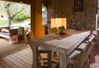 Interno della tenda safari Spotty Lodge al Weekend Glamping Resort in Italia, con arredi in legno e patio esterno.