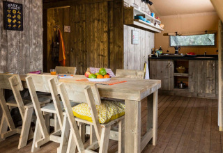 Interno della tenda safari Spotty Lodge con arredi in legno e cucina al Weekend Glamping Resort, Italia.