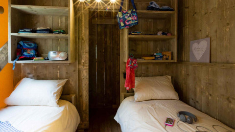 Due letti singoli con pannelli in legno e scaffali presso Spotty Lodge, Weekend Glamping Resort, Italia.