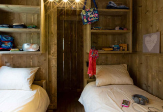 Due letti singoli con pannelli in legno e scaffali presso Spotty Lodge, Weekend Glamping Resort, Italia.
