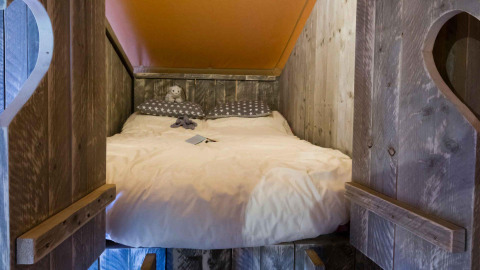 Accogliente letto incassato nella tenda Spotty Lodge al Weekend Glamping Resort, Italia, con pareti in legno rustico.