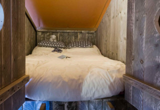 Accogliente letto incassato nella tenda Spotty Lodge al Weekend Glamping Resort, Italia, con pareti in legno rustico.