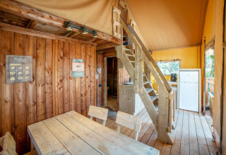 Indvendig udsigt over Safari Lodge telt på Weekend Glamping Resort i Italien med træmøbler og trappe.