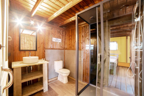 Badeværelse i Safari Lodge-safaritelte i Weekend Glamping Resort, Italien, med trævægge og moderne faciliteter.