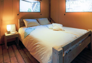 Soveværelse i Safari Lodge telt på Weekend Glamping Resort i Italien med dobbeltseng og hyggelig belysning.