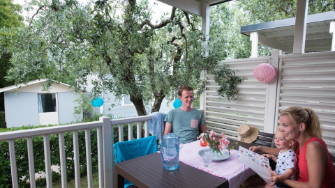 Family enjoys breakfast on the terrace at the Next L Deluxe lodge, Weekend Glamping Resort, Italy.
