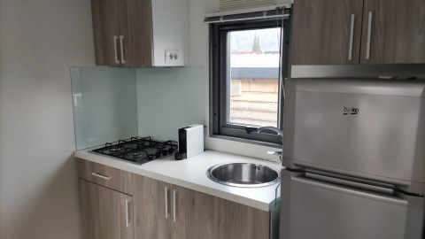 Modern kitchenette at Next L Deluxe Weekend Glamping Resort in Italy with stove, fridge, and window view.